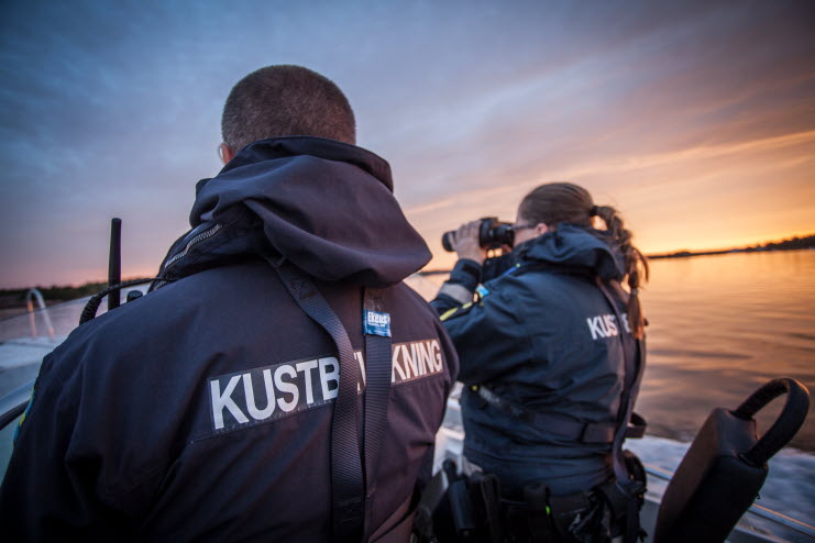 Kustbevakare spanar över havet i solnedgång